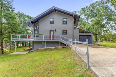 Rear view of property with a deck, driveway, a yard, a garage, and stairway
