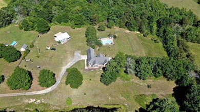 View of property including 7+ acres, pond, detached garage, inground pool, one level custom brick home.