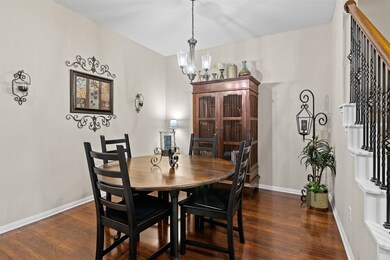 The dining room has laminate wood floors, chandelier and high ceilings.