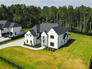 View of front facade featuring driveway, a shingled roof, a garage, and a wooded view