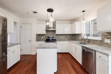 Kitchen featuring a center island, appliances with stainless steel finishes, decorative backsplash, white cabinets, and a textured ceiling