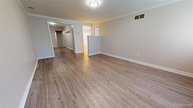 Empty room featuring crown molding and light wood finished floors