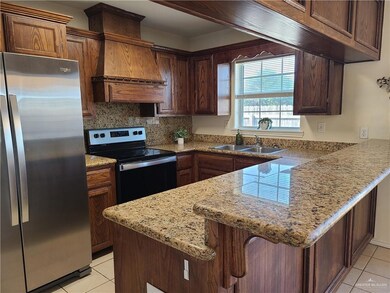 Kitchen with appliances with stainless steel finishes, light tile patterned floors, a peninsula, and custom exhaust hood