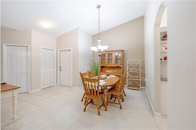 Dining room featuring lofted ceiling, arched walkways, a chandelier, light colored carpet, and light tile patterned floors