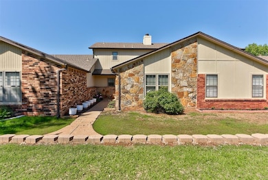 View of front of house with stone siding, a front yard, and a chimney