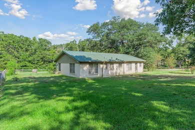 Rear view of house featuring brick siding, a metal roof, and view of wooded area