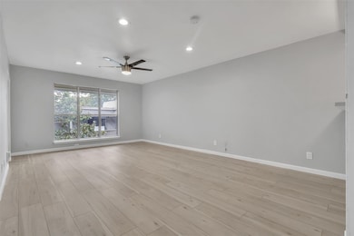 Empty room with ceiling fan and light wood-type fl