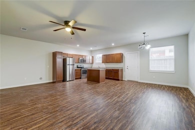 Kitchen featuring open floor plan, stainless steel appliances, decorative light fixtures, dark wood-style flooring, and recessed lighting
