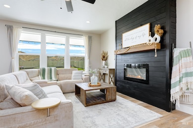 Living room featuring wood finished floors, a large fireplace, recessed lighting, and a ceiling fan