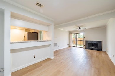 Unfurnished living room with ornamental molding, light wood-style flooring, a fireplace with flush hearth, and a ceiling fan