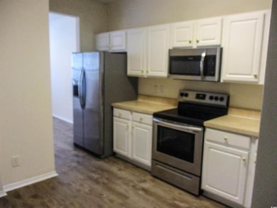 Kitchen with appliances with stainless steel finishes, white cabinetry, and light countertops