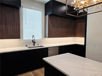Kitchen featuring a sink, light stone countertops, a chandelier, and modern cabinets