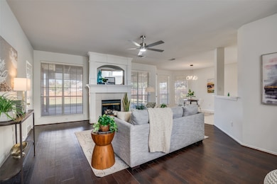 Living area featuring a tile fireplace, dark wood finished floors, a chandelier, and ceiling fan