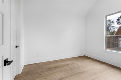 Empty room featuring light wood finished floors and lofted ceiling
