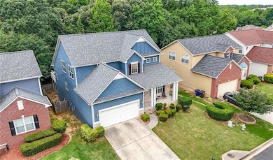 View of front of home with an attached garage, driveway, covered porch, board and batten siding, and stone siding