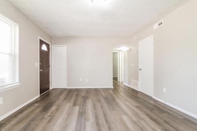 Unfurnished living room with wood finished floors and baseboards