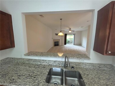 Kitchen with a tile fireplace, ceiling fan, light stone counters, decorative light fixtures, and open floor plan
