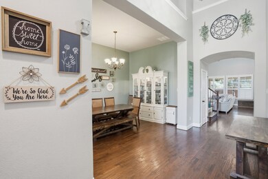 Dining area with dark wood-style flooring, a chandelier, a high ceiling, and arched walkways