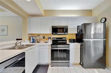Kitchen with stainless steel appliances, light countertops, white cabinetry, and a textured ceiling