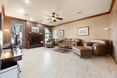 Living area with crown molding, a brick fireplace, and ceiling fan