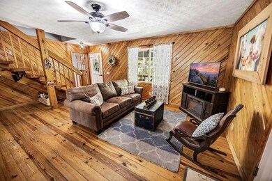 Living area with stairs, wood walls, a ceiling fan