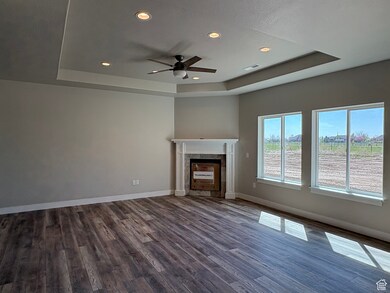 Unfurnished living room featuring a raised ceiling, recessed lighting, and dark wood-style floors