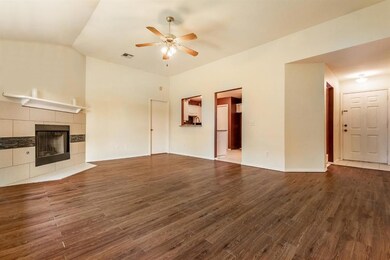Unfurnished living room featuring a ceiling fan, a tiled fireplace, dark wood finished floors, and lofted ceiling