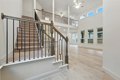 Stairway with wood finished floors, plenty of natural light, a ceiling fan, and a towering ceiling
