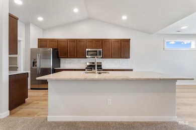 Kitchen featuring appliances with stainless steel finishes, recessed lighting, decorative backsplash, vaulted ceiling, and light stone counters