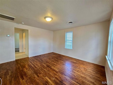 Spare room with wood finished floors and a textured ceiling