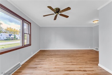 Empty room featuring crown molding, light wood-type flooring, and ceiling fan