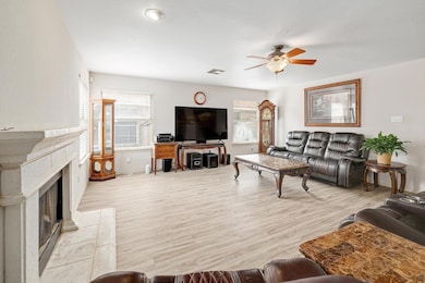 Living room with ceiling fan, a fireplace with ra