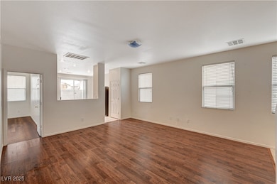 Empty room featuring dark wood-style floors and he