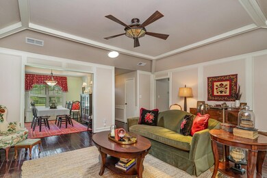 Living room featuring lofted ceiling, ceiling fan, and dark wood-type flooring