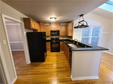 Kitchen featuring black appliances, light hardwood