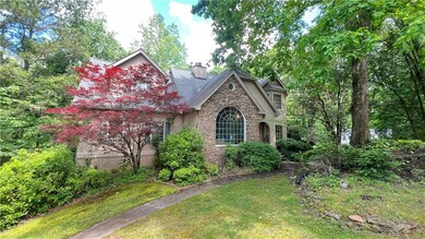 View of front of house featuring stone siding, a chimney, and a front yard