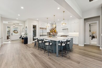 Kitchen featuring white cabinets, a breakfast bar, pendant lighting, a spacious island, and light wood-style flooring