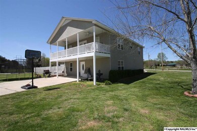 Showing the concrete drive and the covered patio on main level and deck on upper level.