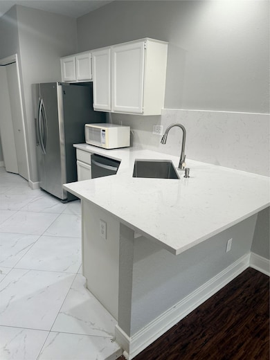 Kitchen featuring a peninsula, white cabinetry, l