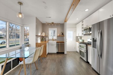 Kitchen featuring white cabinets, appliances with stainless steel finishes, open shelves, decorative backsplash, and dark wood-style floors