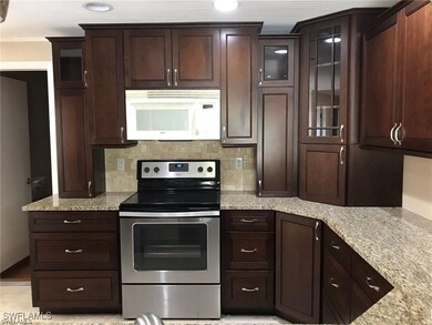 Kitchen with light stone counters, dark brown cabi