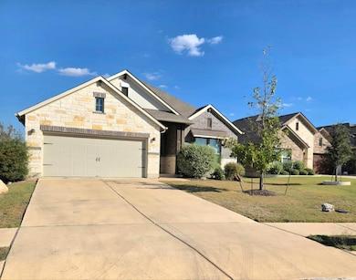 View of front facade with concrete driveway, a front yard, stone siding, an attached garage, and brick siding