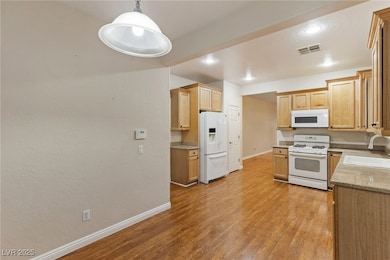 Kitchen featuring visible vents, white appliances,