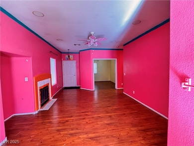 Unfurnished living room featuring dark wood-style floors, a ceiling fan, a tile fireplace, and crown molding