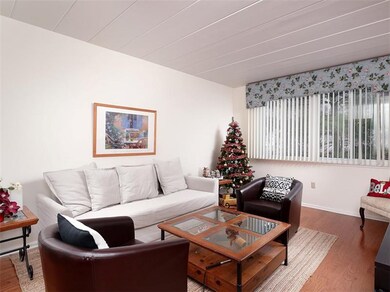 The living room has neutral dcor, hardwood floorin