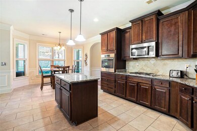 At the heart of the home, the Open Kitchen features Granite Countertops, a Large Center Island, Stained Cabinets, Stainless Steel Appliances, and a bright Breakfast Nook surrounded by windows.