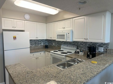 Kitchen featuring white appliances, sink, backspla