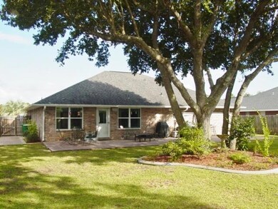 Rear of home with majestic oak trees in large back yard.