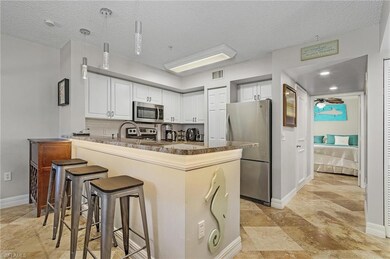 Kitchen featuring white cabinetry, a breakfast bar, stainless steel appliances, pendant lighting, and a peninsula