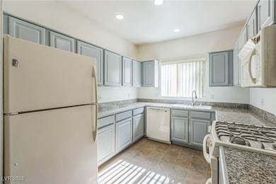 Kitchen featuring white appliances, gray cabinets, and recessed lighting
